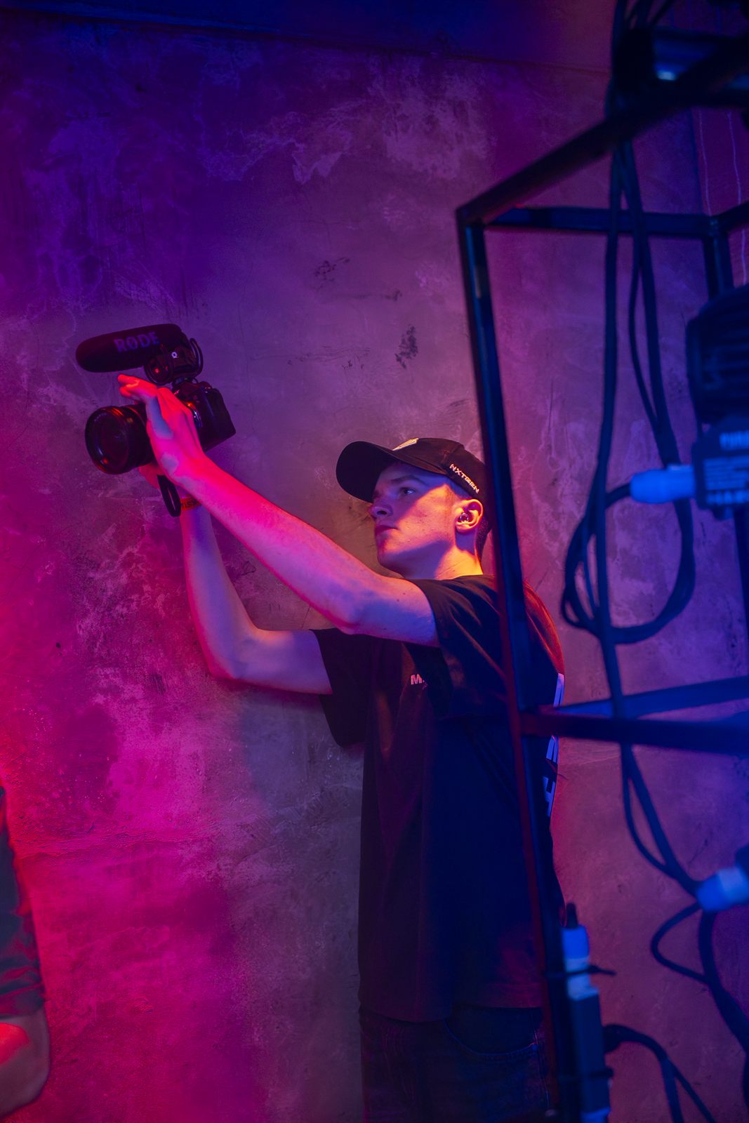 Wesley filmt met camera en microfoon in paars en roze licht
