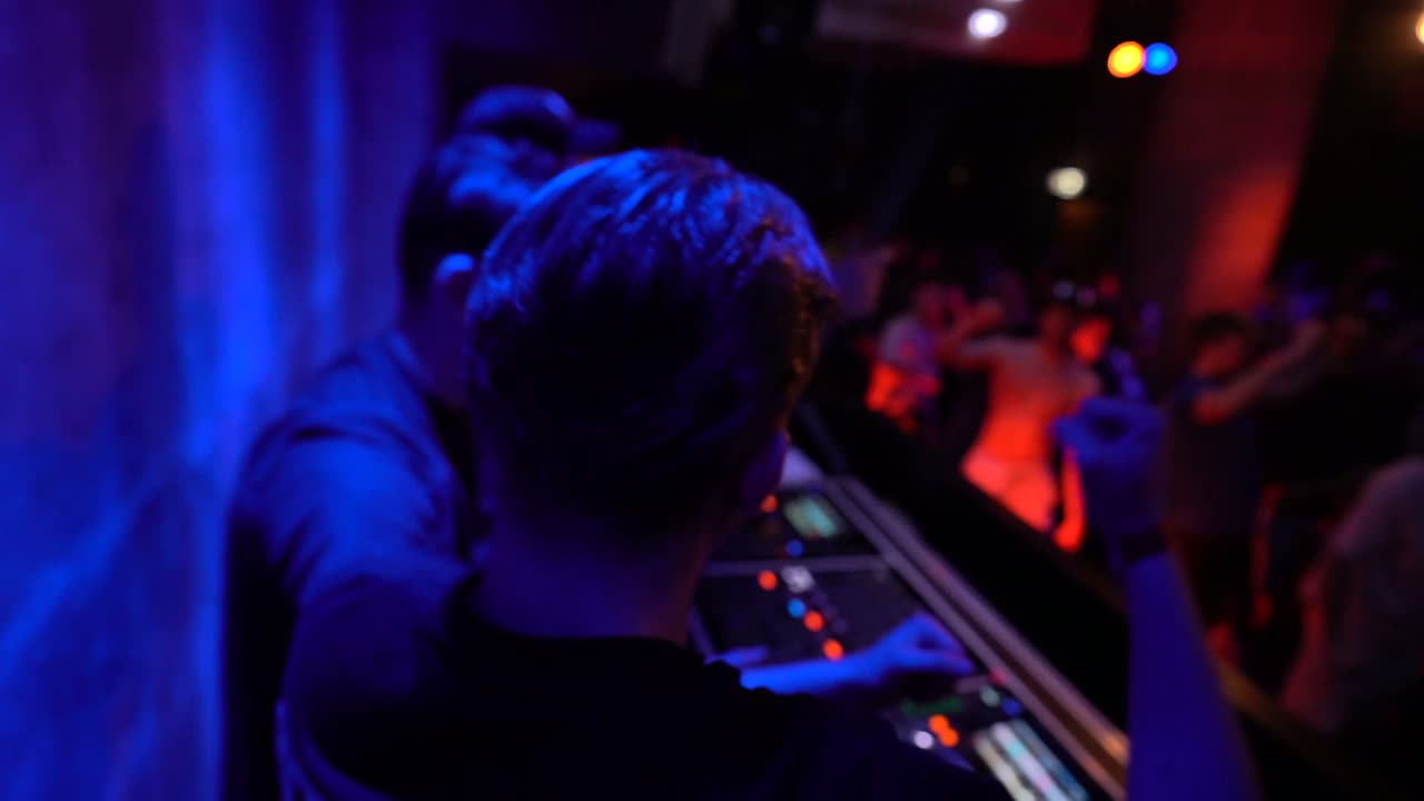 DJ-booth in blauw licht met dansend publiek