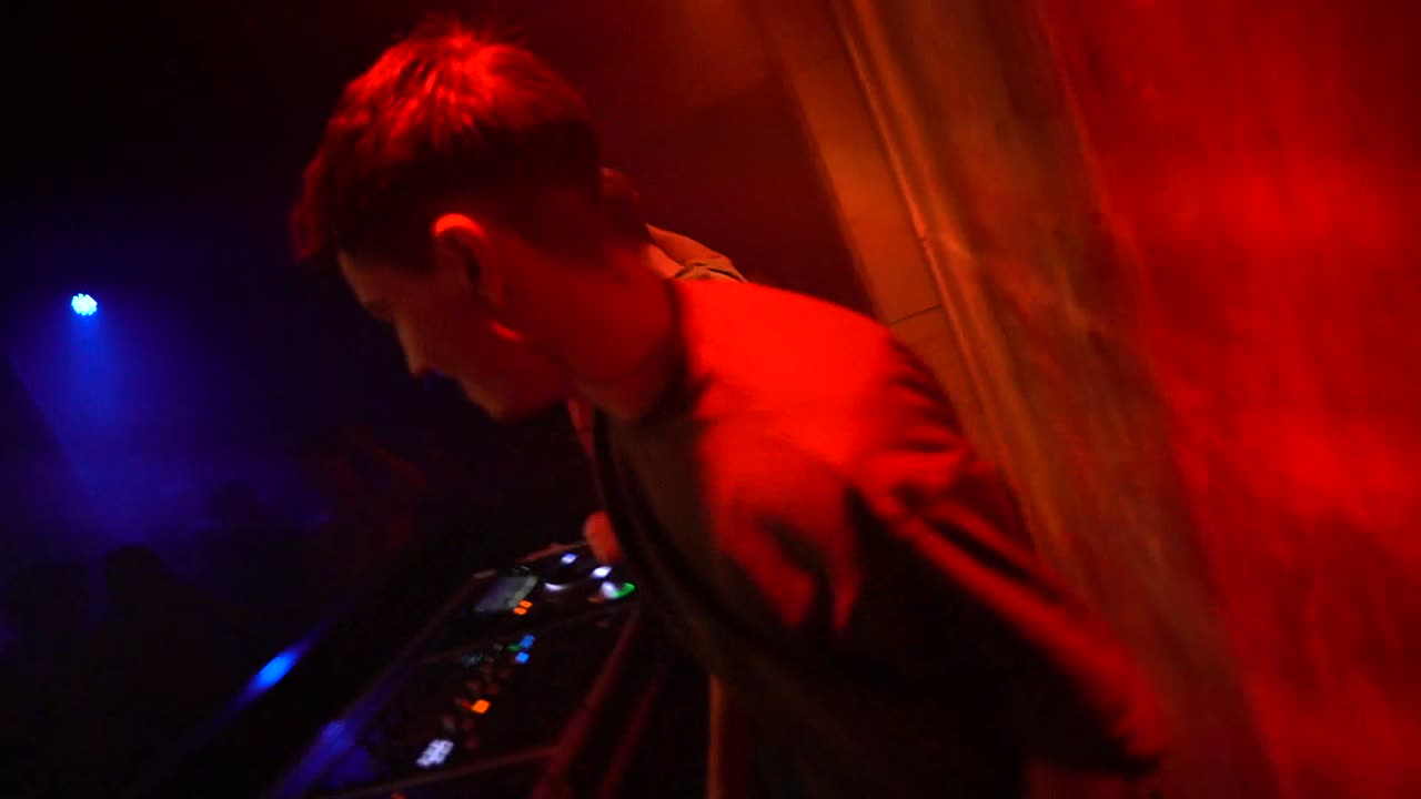 DJ in rood licht met publiek in de rook
